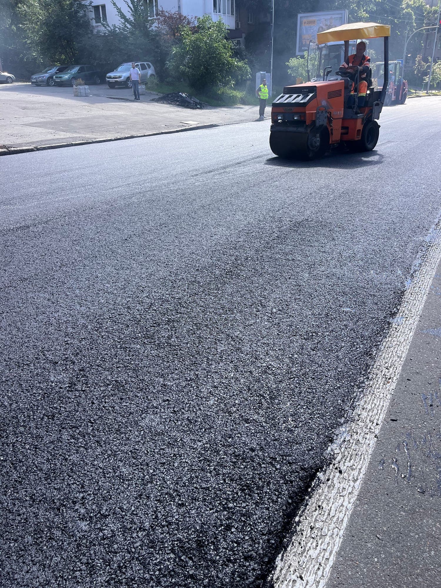 Compacting the MZ A-20 surface course with a roller on Mykhaila Boichuka Street