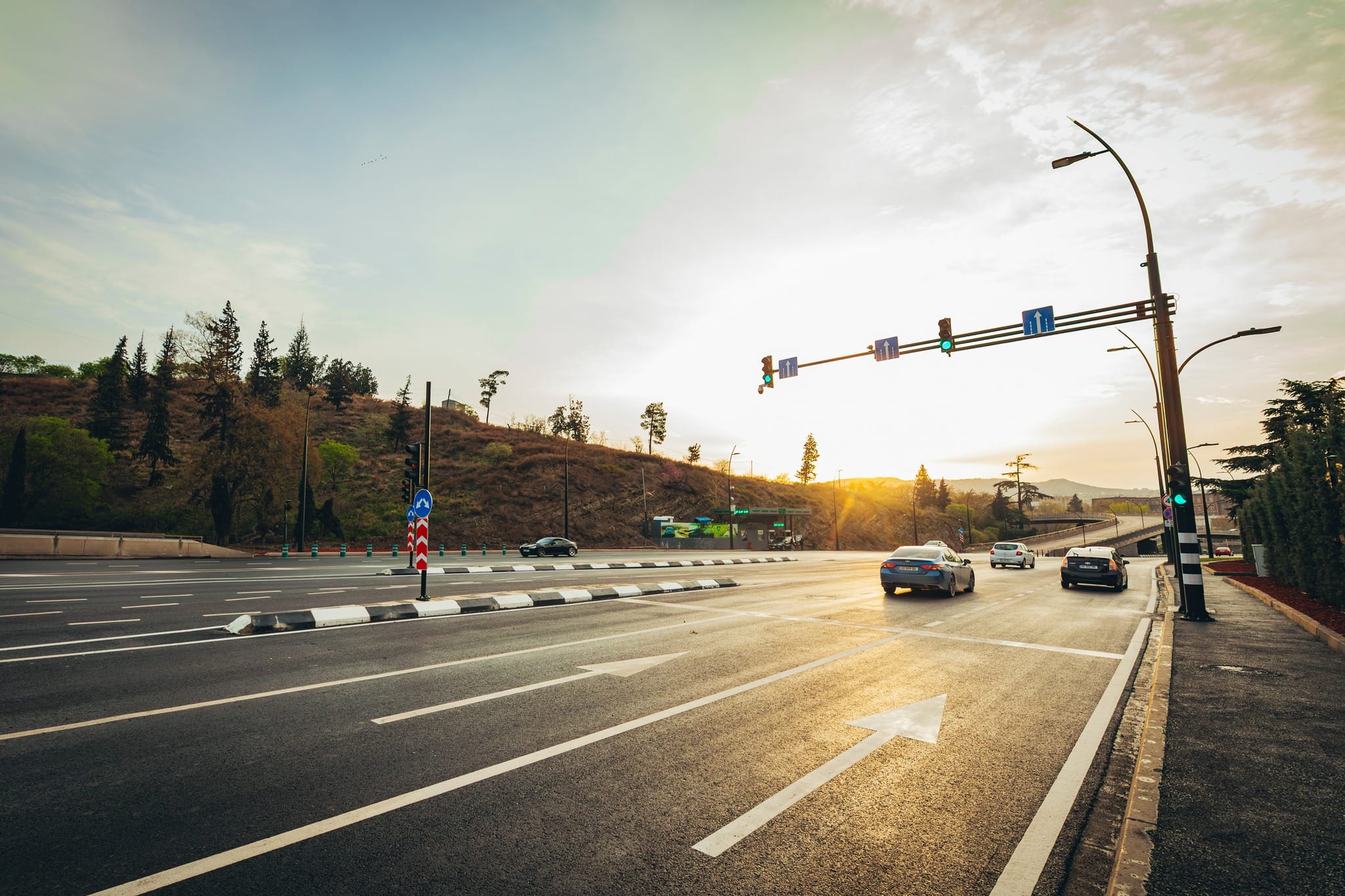 Una avenida urbana al atardecer: marcas viales nuevas, mediana y tráfico