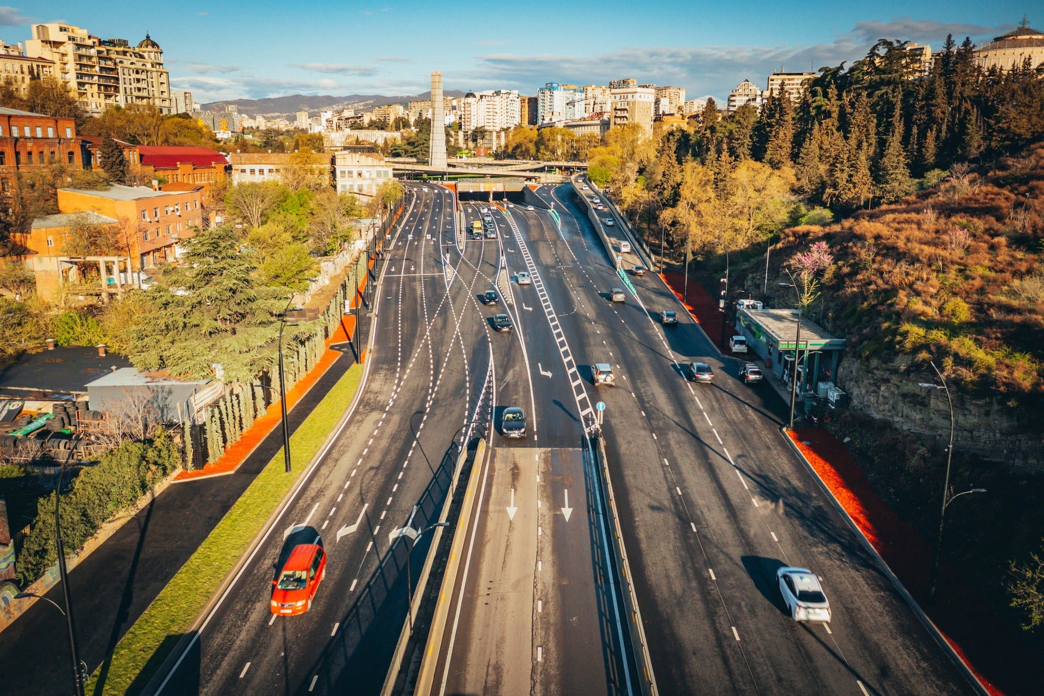 Una arteria urbana en servicio: calzadas separadas, carriles reservados, la entrada a un paso inferior