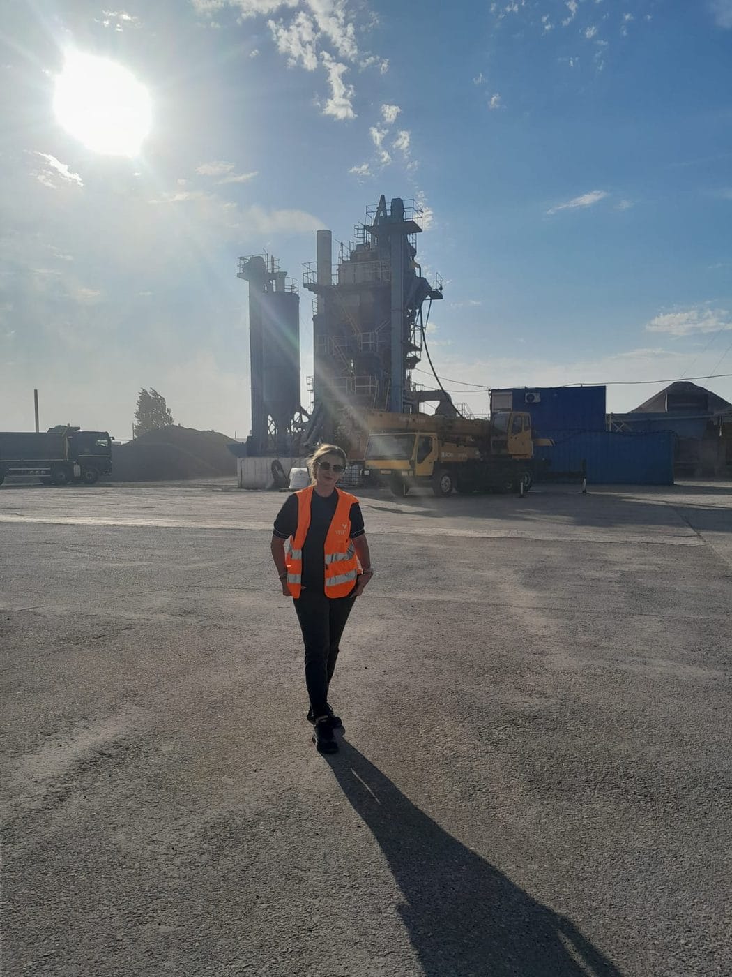 Un collaborateur en gilet traverse l'aire de la centrale, l'installation derrière