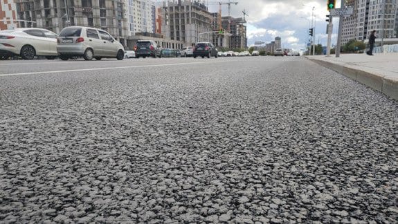 A textura do pavimento concluído em detalhe, uma rua da cidade ao fundo