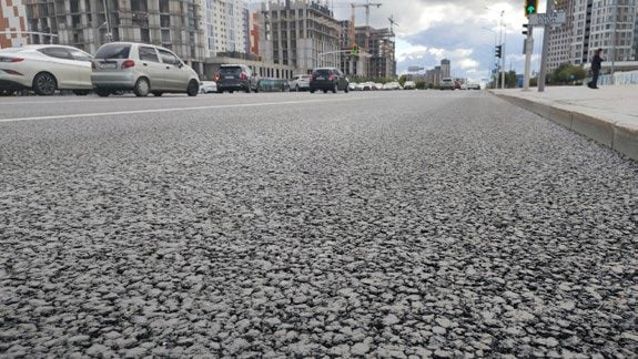 A textura do pavimento concluído em detalhe, uma rua da cidade ao fundo