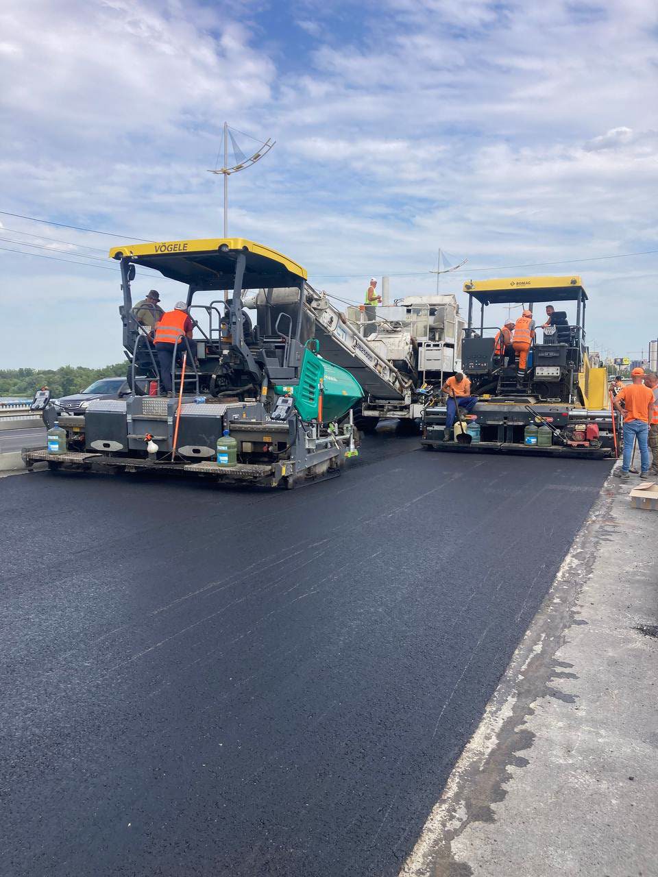 Una pavimentadora y un rodillo en el puente, la cuadrilla al lado