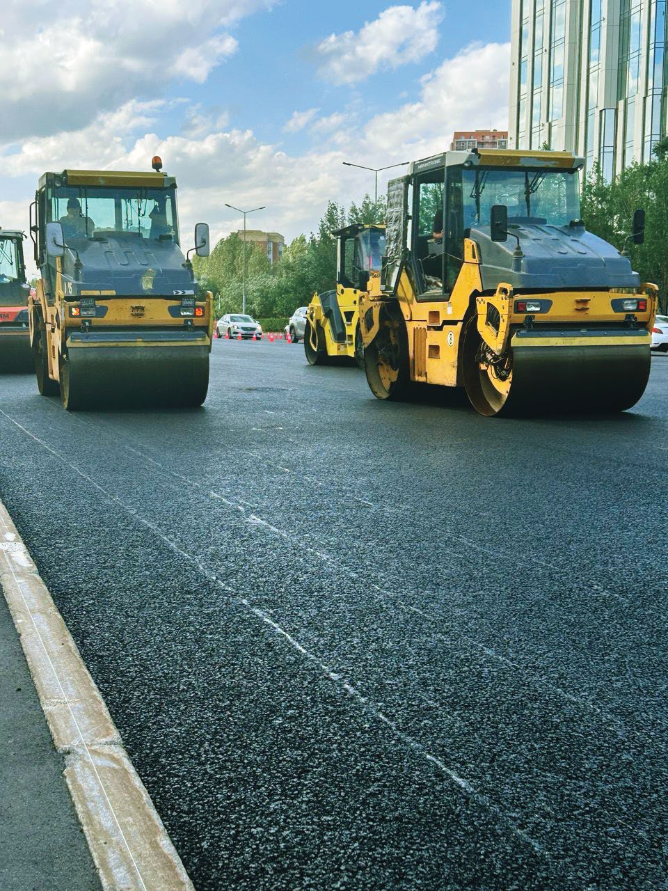 Dos rodillos compactan la capa fresca en un carril urbano