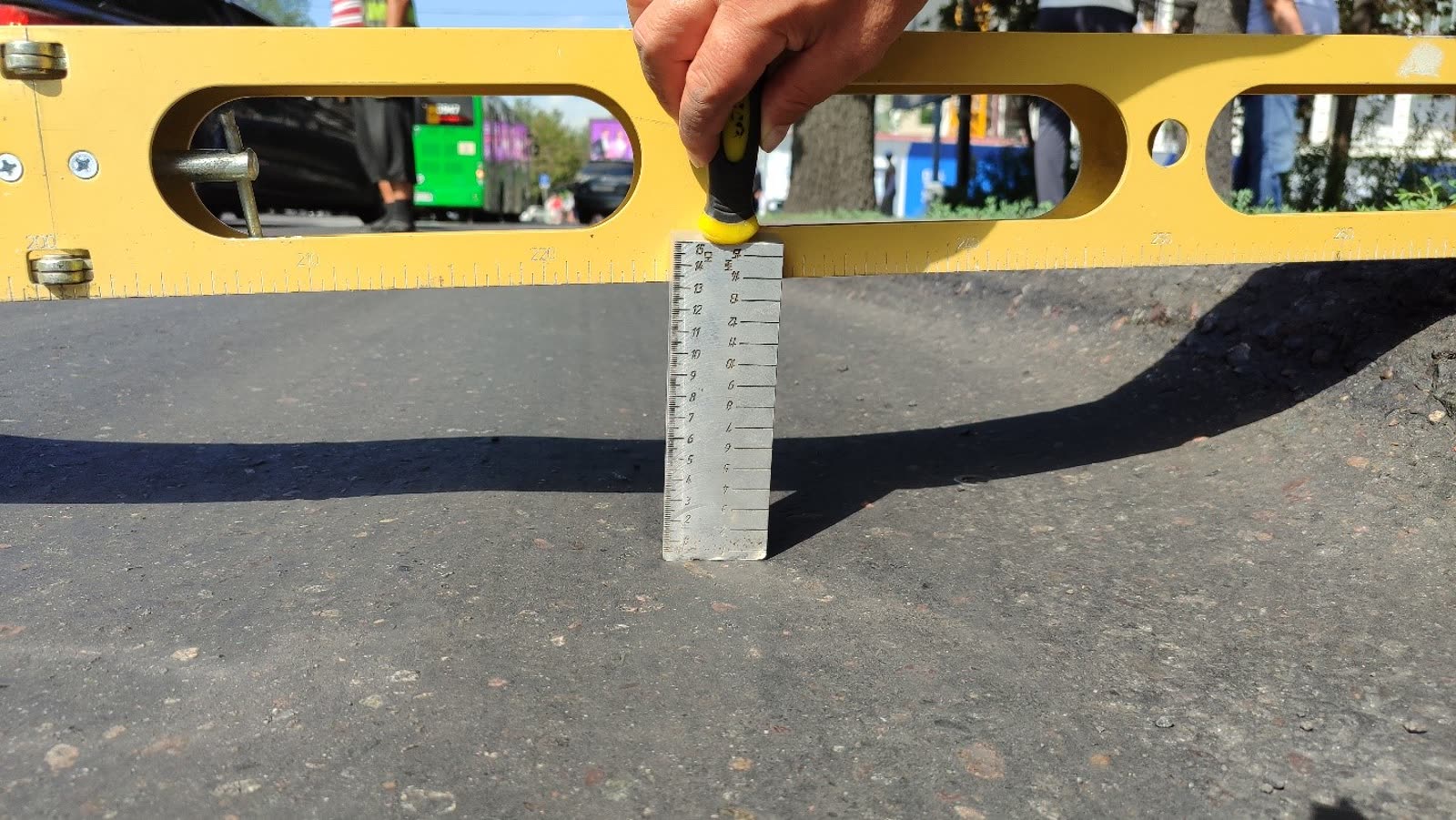 Measuring rut depth with a gauge under a straightedge on the pavement